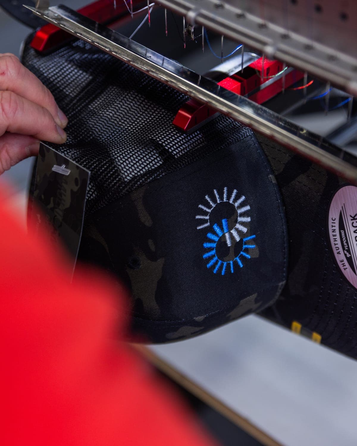 Lining up a camo snapback on the embroidery machine