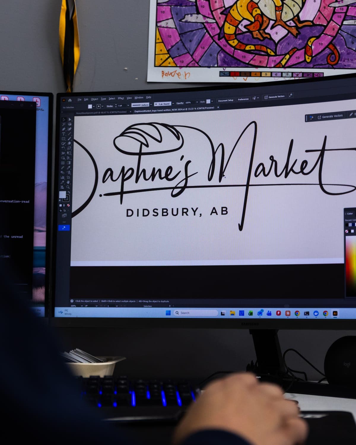 Daphne's Market script logo being drawn on a designer's monitor