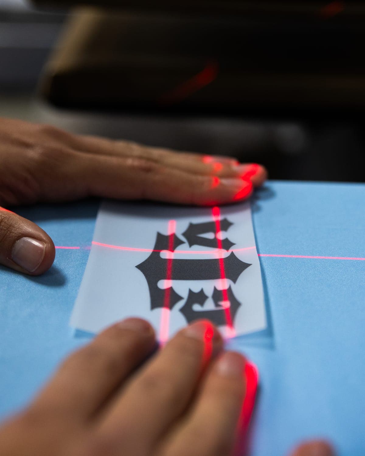 Lining up a DTF transfer on a shirt with the heat press's laser guides