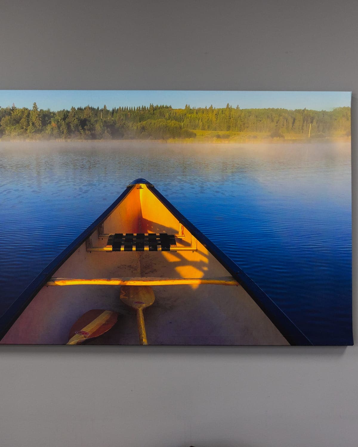 Canvas print of a canoe on a misty lake hanging on the shop wall