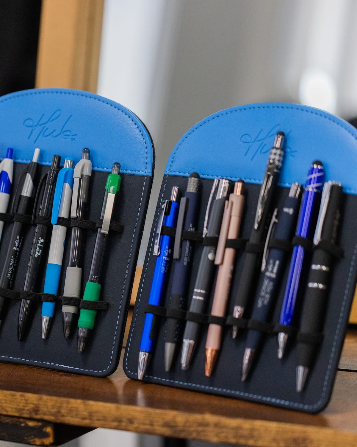 Two leather pen cases filled with branded pens