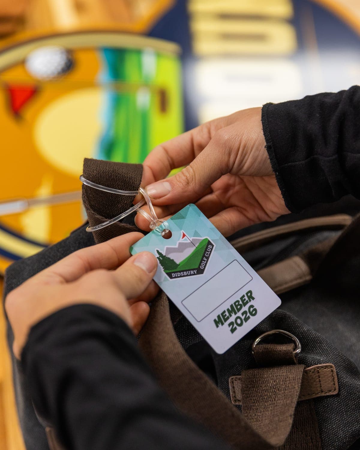 Member 2026 bag tag being tied to a backpack